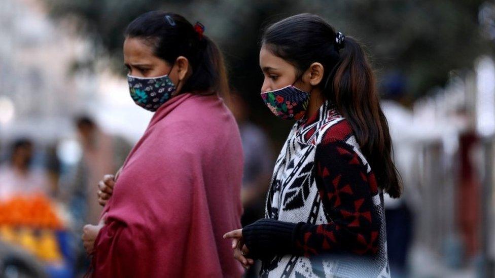 Women with masks against COVID-19 walk outside a market in Karachi, Pakistan January 25, 2021