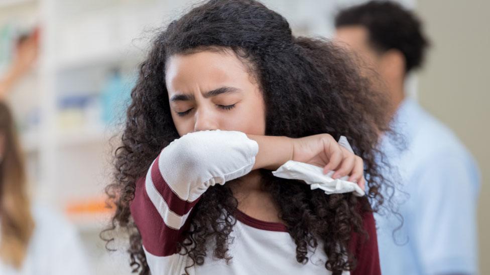 Woman sneezing into her elbow