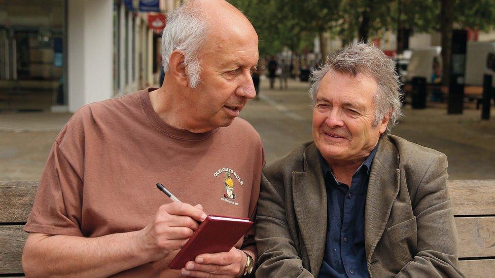 Two men in street with note pad