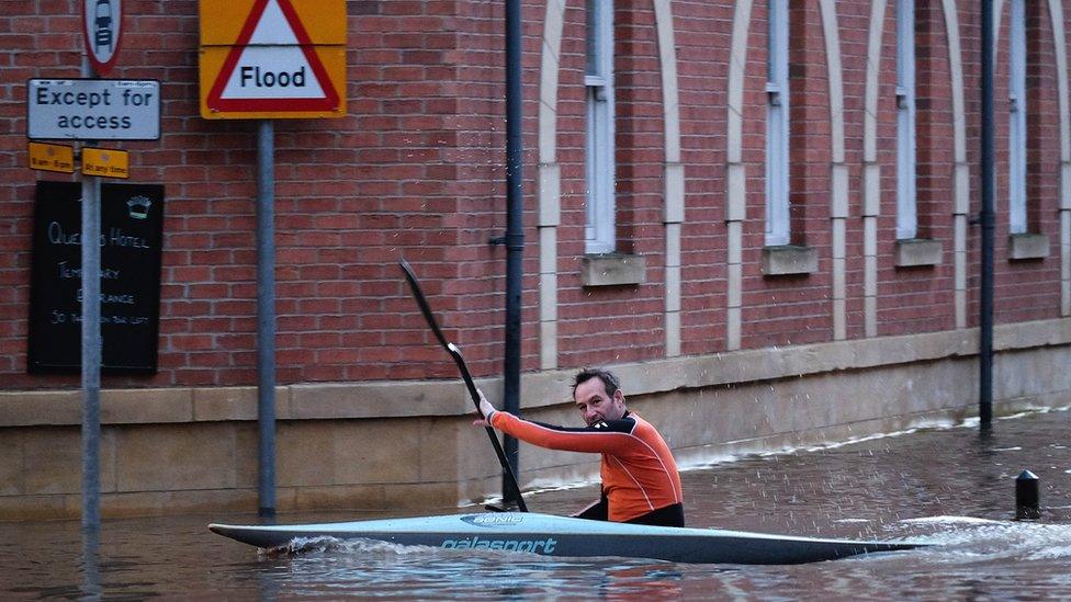 A man paddles his kayak along a flooded street in York, England