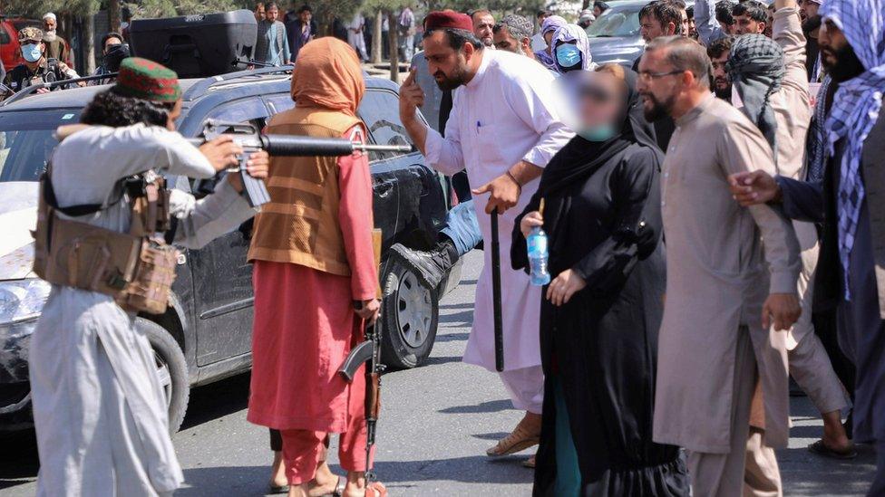 A Taliban fighter points his gun at protesters in Kabul, 7 Sept