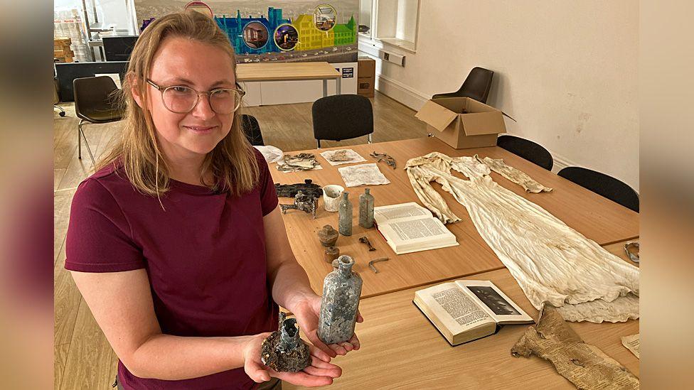 A photo of Jessica Domiczew holding recovered artefacts