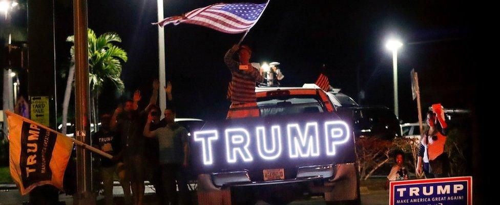 Supporters of President-elect Donald Trump wave to his passing motorcade