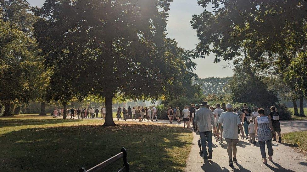 A group of people walking towards some trees