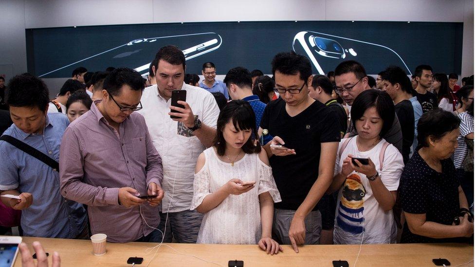 Customers trying out an iPhone 7 in a shop in China