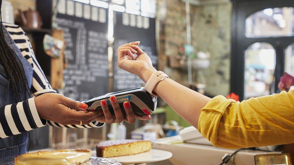 Young woman paying for goods with a smart watch in a coffee shop