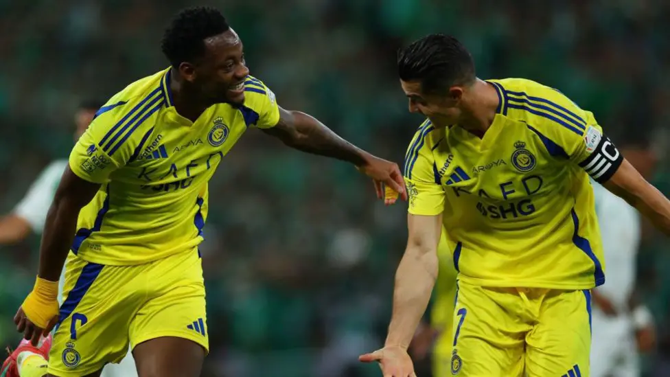 Jhon Duran and Cristiano Ronaldo celebrating together while wearing Al-Nassr's bright yellow kit