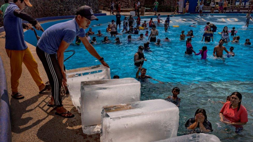 Workers putting blocks of ice into a swimming pool in the Philippines