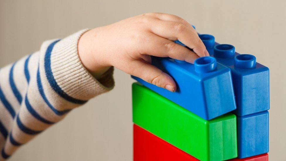 Preschool age child playing with plastic building blocks