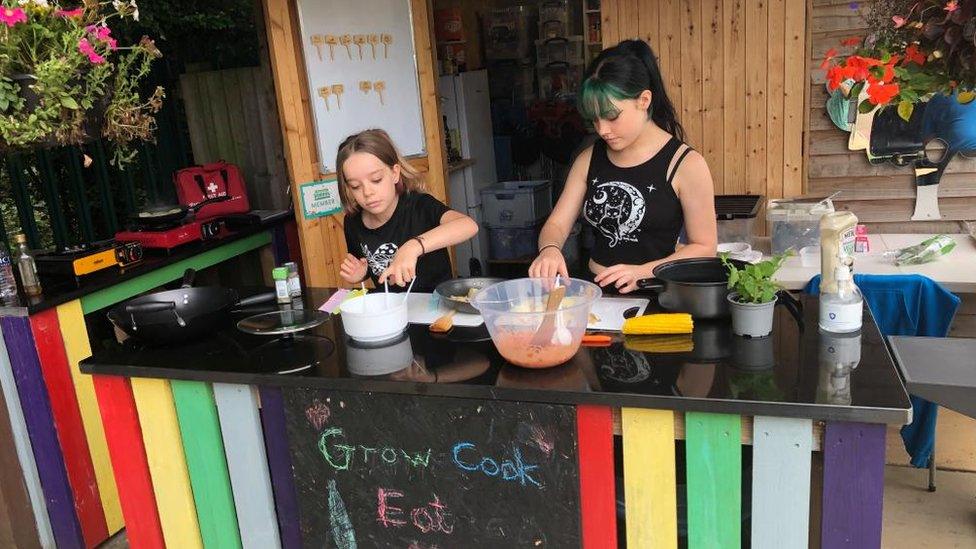 Two children with mixing bowls and ingredients