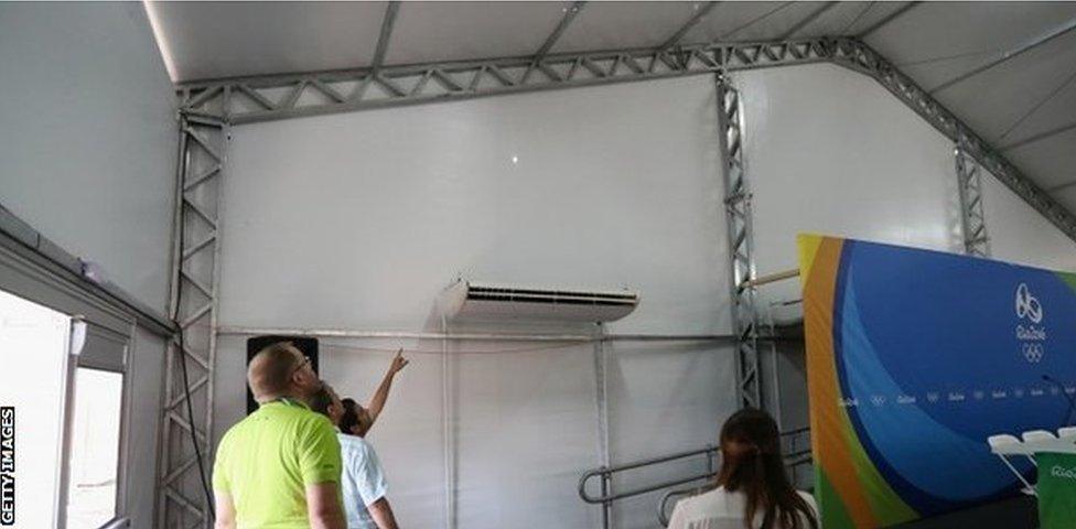 Staff look at a bullet hole inside the media centre at the Olympic Equestrian Centre