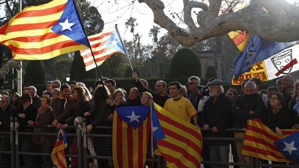 People wave "estelada" or pro-independence flags prior to the investiture session at the Catalonian parliament in Barcelona