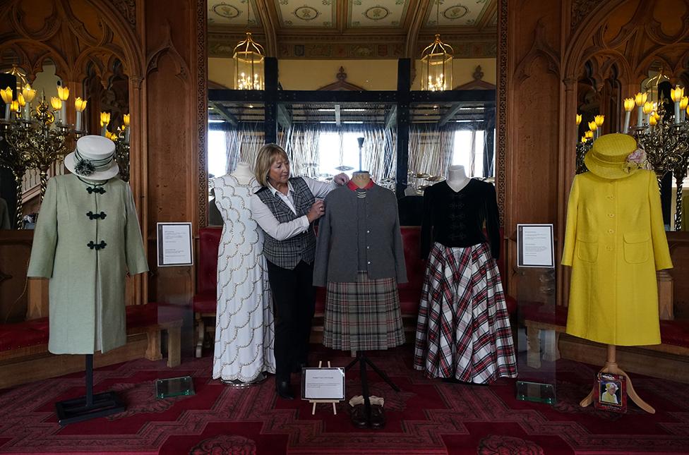 Assistant curator Sarah Hoare adjusts outfits worn by Queen Elizabeth II whilst at Balmoral as they go on display in the Castle Ballroom at the opening of Life at Balmoral