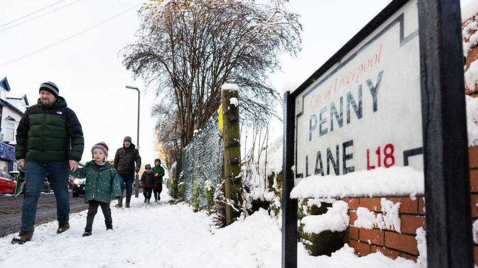 People walk along a snow-covered Penny Lane