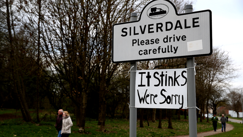 Sign in Silverdale saying Silverdale - Please drive carefully. Someone has added a cardboard sign to it with the words: It stinks, we're sorry