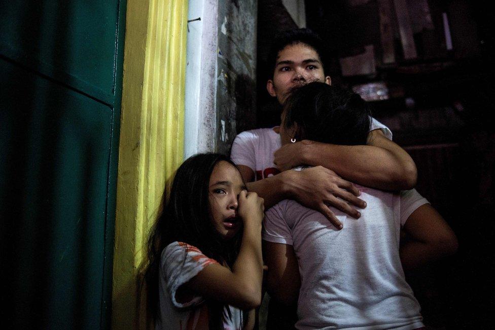 This picture taken on 5 January 2017, shows relatives crying as coroners carry away the body of an alleged drug dealer killed during a drug buy bust operation in Manila