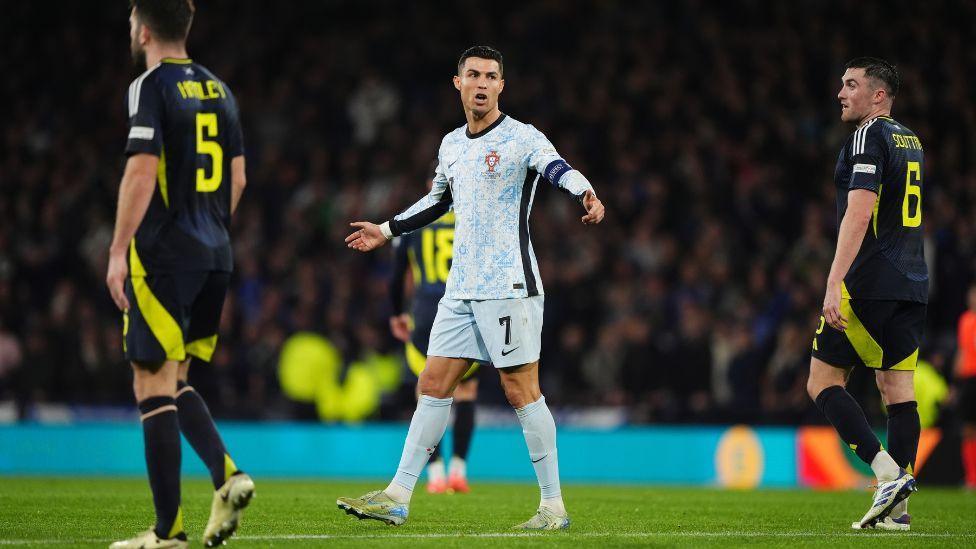 Ronaldo at Hampden Park between two Scotland players