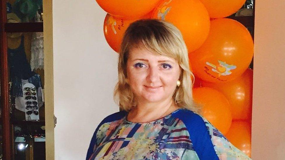 Victoria Valkovskaya, a blonde woman who is pictured in a blue dress in front of an arch made from orange balloons