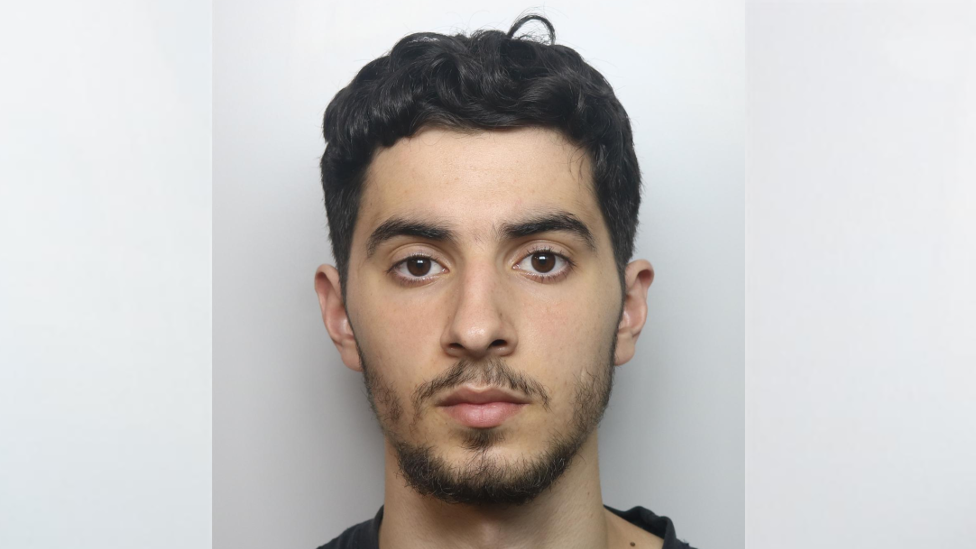 A mugshot of Ilias Almallah, who has short, black hair, a short black beard and is looking ahead, expressionless 