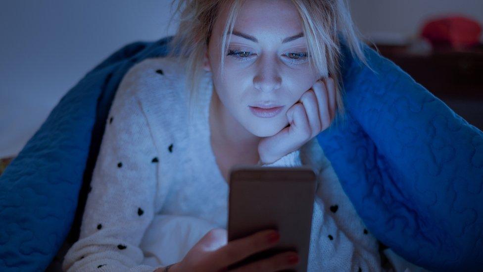 A woman using her phone in bed