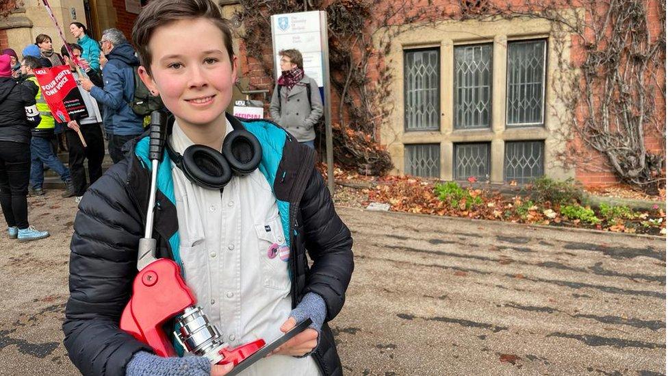 A student at the University of Sheffield holding a machine being used to make badges