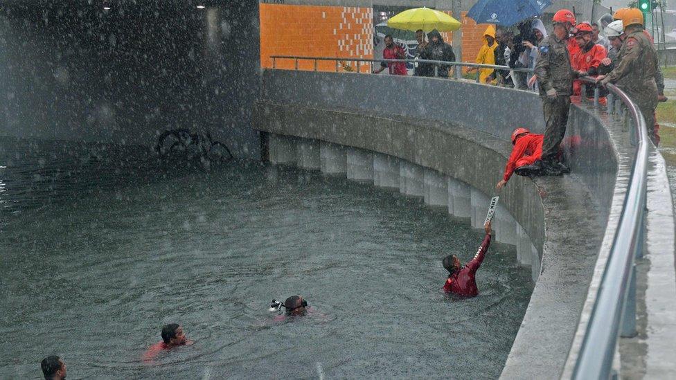 A firefighter retrieves a licence plate from a submerged car