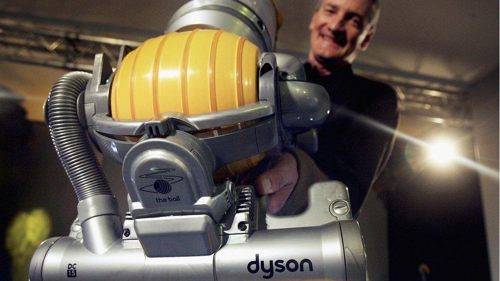 Sir James Dyson holds up a vacuum cleaner