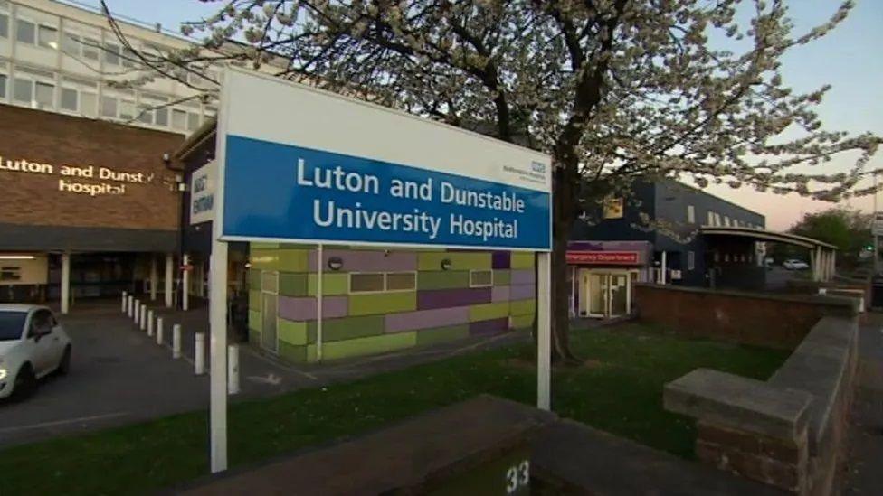 Blue and white name sign outside Luton and Dunstable Hospital