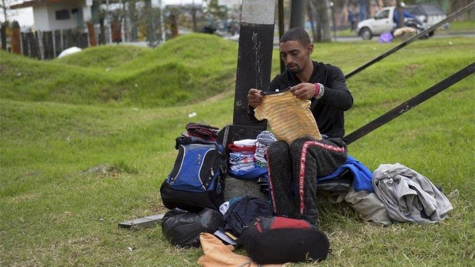 A Venezuelan migrant sorts out donated clothes at an improvised camp near a bus terminal in Bogota on September 11, 2018