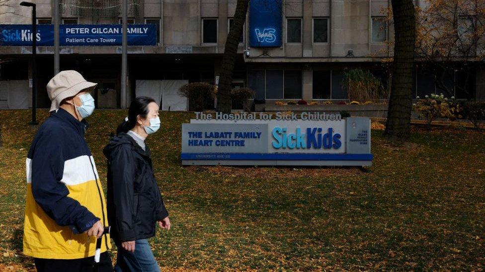 Two people walk outside the Hospital for Sick Children in Toronto, Canada.