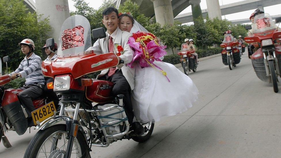 A Chinese bride and groom on a motorcycle