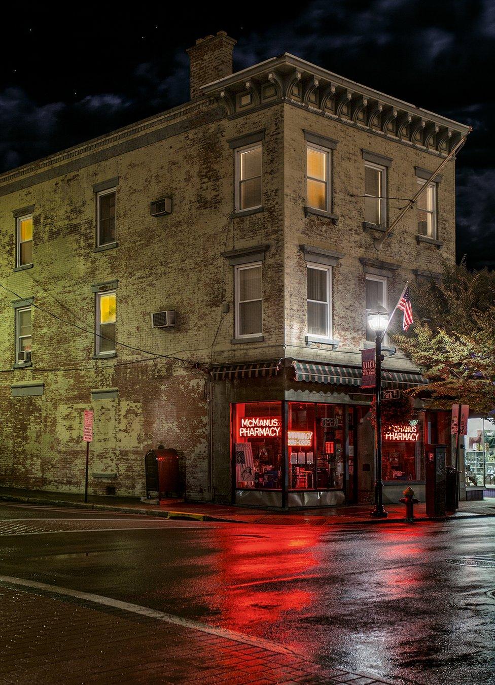 A night view of a closed pharmacy with a red neon sigh in the window