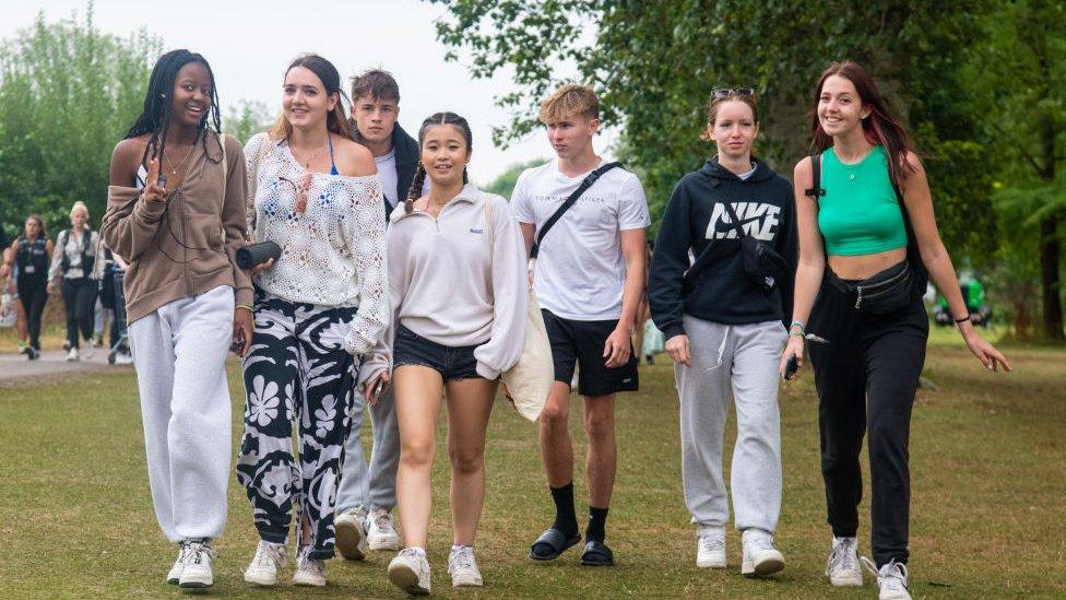 Festivalgoers walk towards the campsite gates with their camping gear