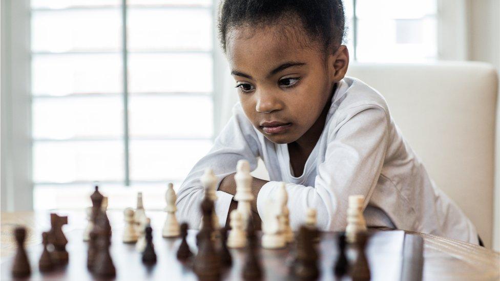 A young girl plays a game of chess