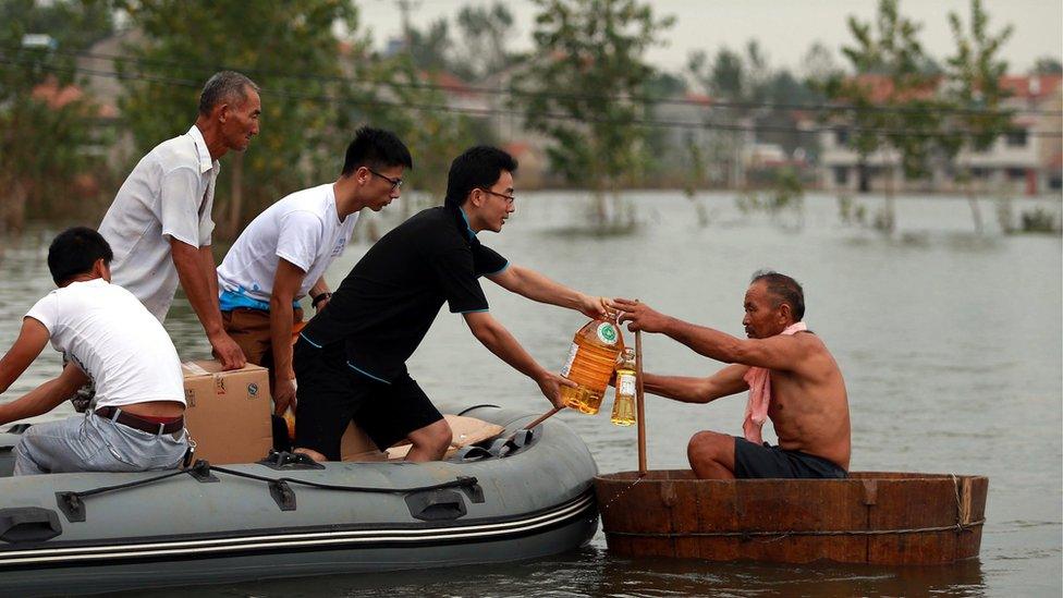 A picture made available on 23 July 2016 of volunteers giving food supplies to a villager in a makeshift boat on flood water, Xinhua Village of Xinchang county in Wuhan city, Hubei Province of central China on 18 July 2016.