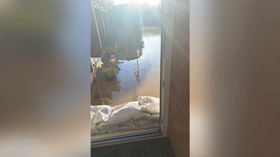 Flood water in the garden with sandbags protecting the back door preventing it from coming into the house