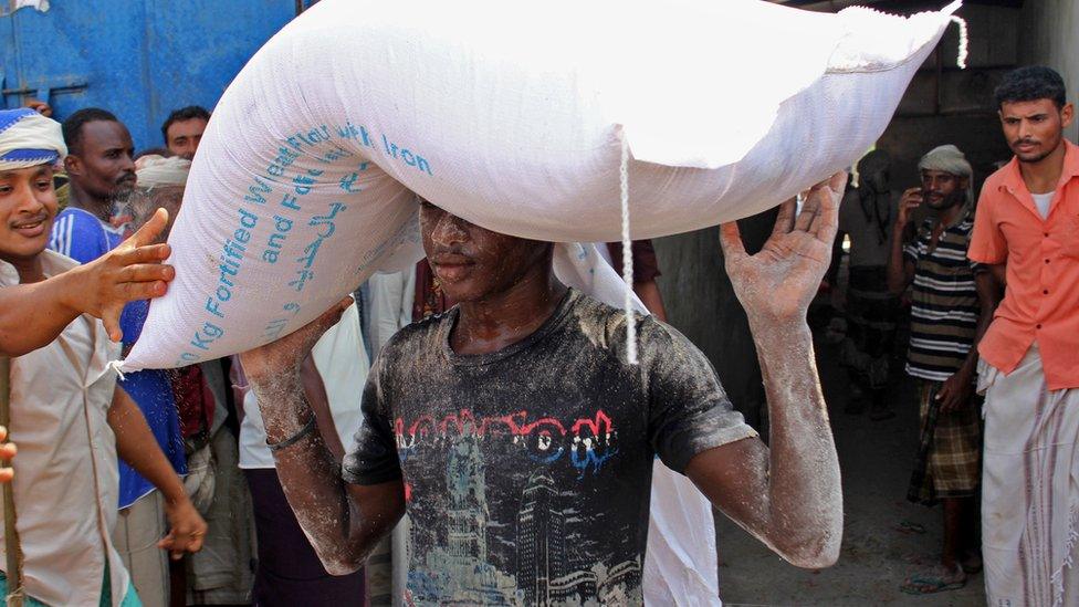 An aid workers carries a sack of flour distributed by the World Food Programme