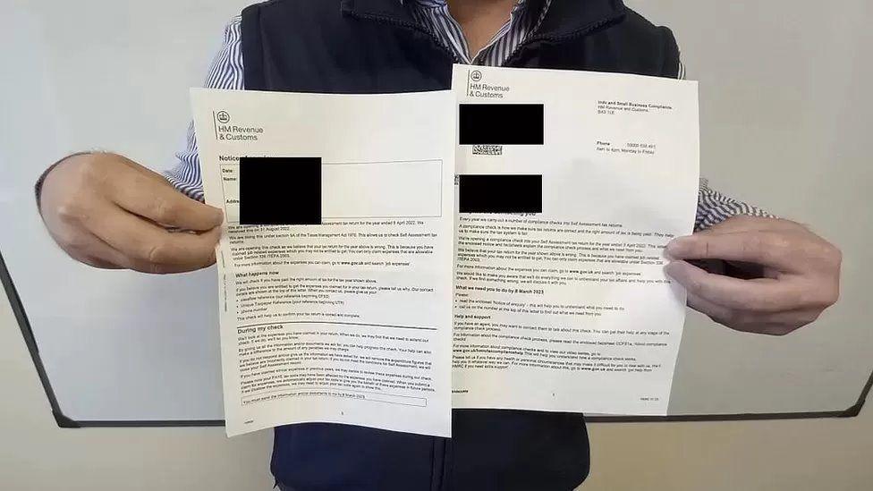 Anonymous man holding a letter from HMRC with sensitive information blacked out