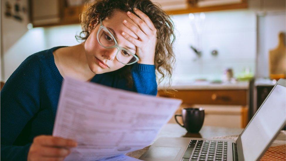 A young woman looking worriedly at bills