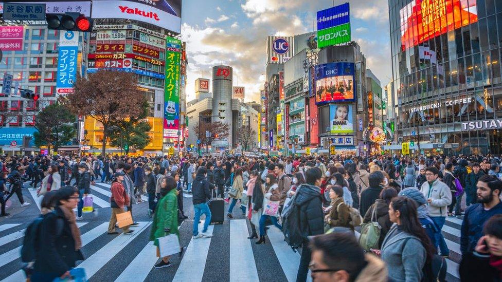 A crowd of pedestrians cross Tokyo's central Shibuya crossing