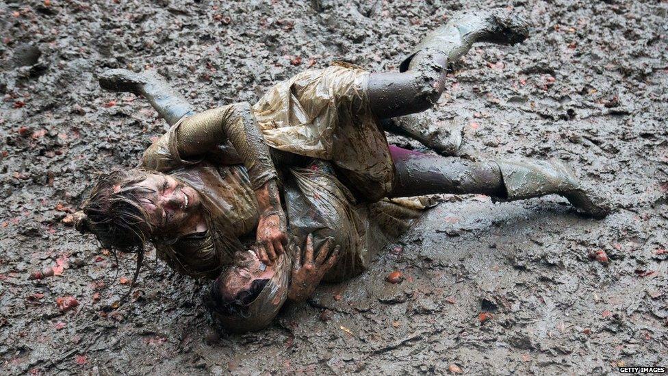 Two women wrestle in the mud at Glastonbury