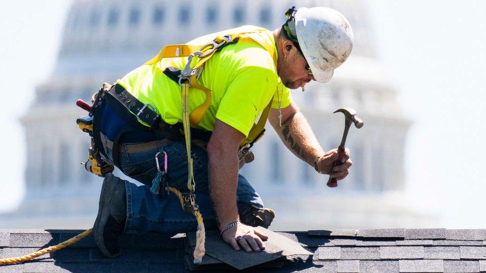 A worker installs shingles on a house on the National Mall in preparation for the Innovative Housing Showcase funded by U.S. Department of Housing and Urban Development and the National Association of Home Builders, on Sunday, June 5, 2022