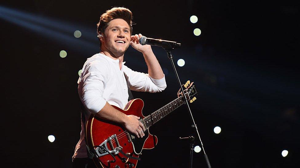 Niall Horan, playing guitar