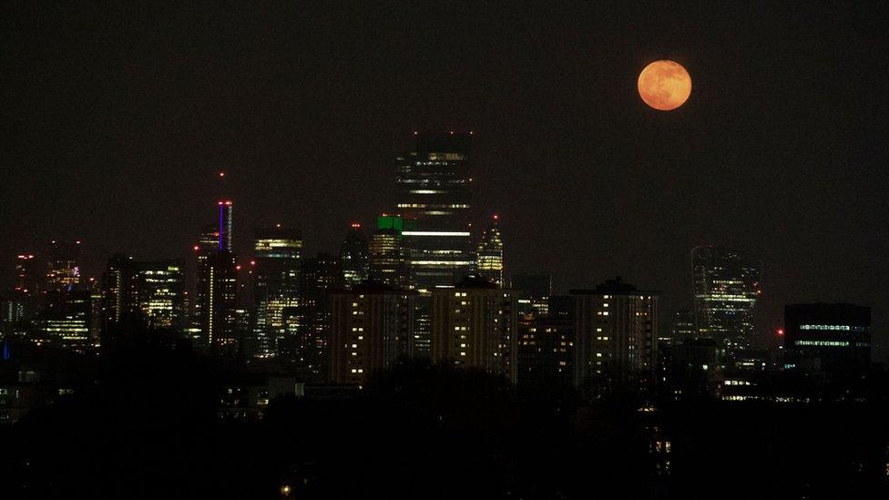 The full moon of April, called the Super Pink Moon, rises over the skyline of London