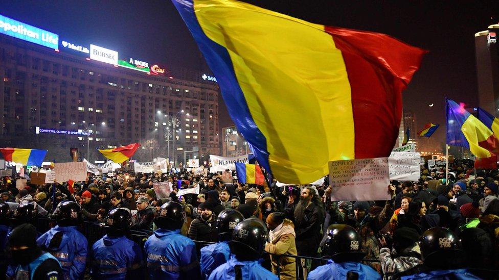 Riot police stand guard as people demonstrate in front of government headquarters in Bucharest, on February 1, 2017