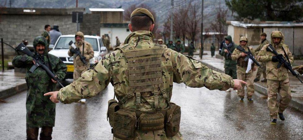 A British soldier giving orders to two rows of troops carrying guns