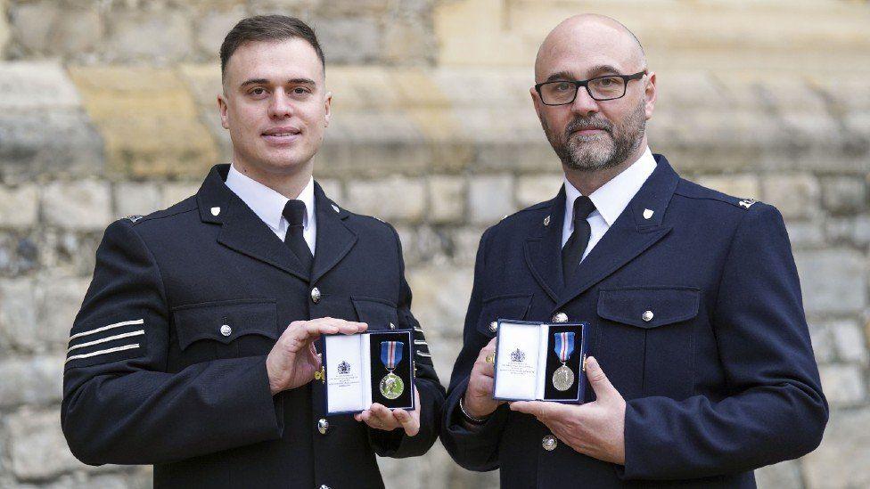 Sgt Michael Hooper, (left) and Constable Stephen Quartermain in their full uniform with navy jackets, white shirts and black ties, holding their medals.