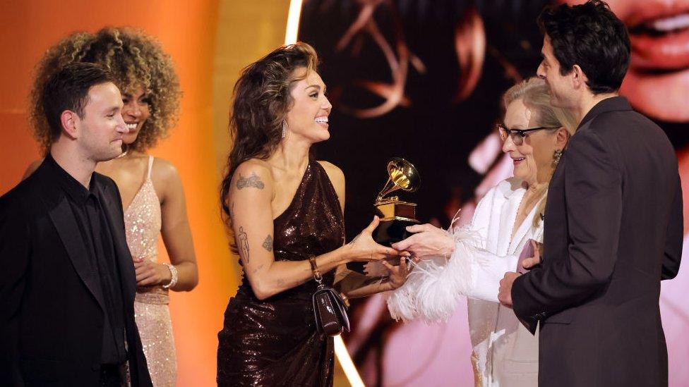 miley cyrus receiving the award for record of the year from actress meryl streep