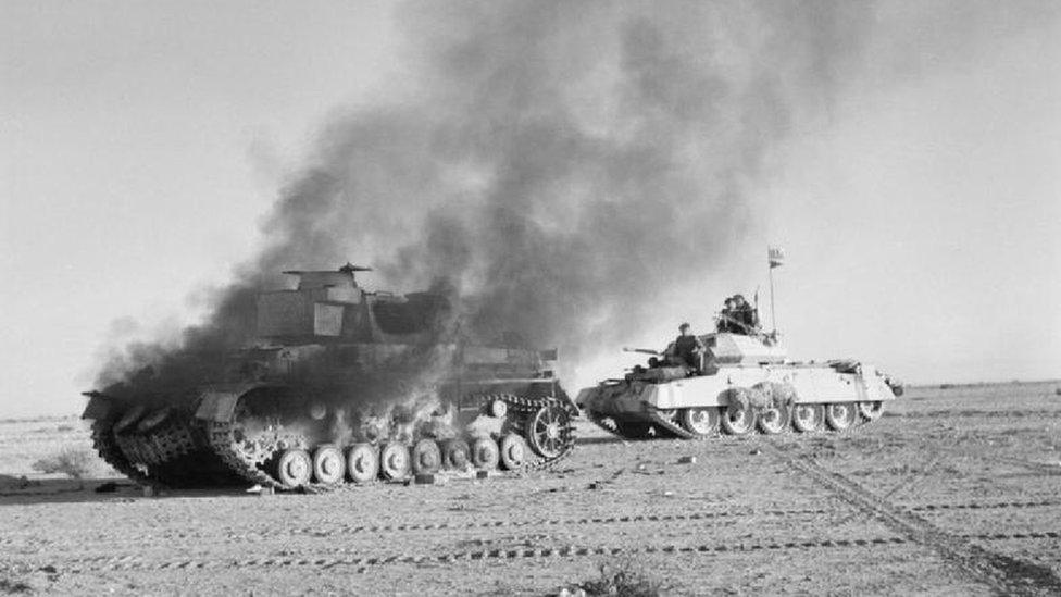 Two tanks - one is on fire in a black and white picture