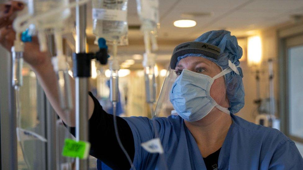 A nurse adjusts intravenous drug dosages being given to a COVID-19 patient in New York